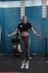 a woman standing in a gym holding a barbell