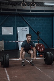 a man squatting down while holding a barbell