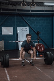 Athlete performing strength training in a modern gym setting with football equipment nearby.