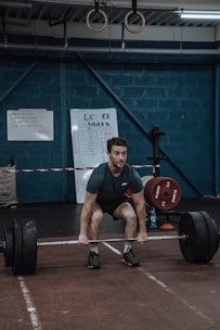 a man squatting down while holding a barbell