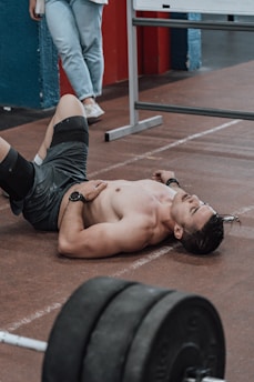 a man laying on the ground with a barbell