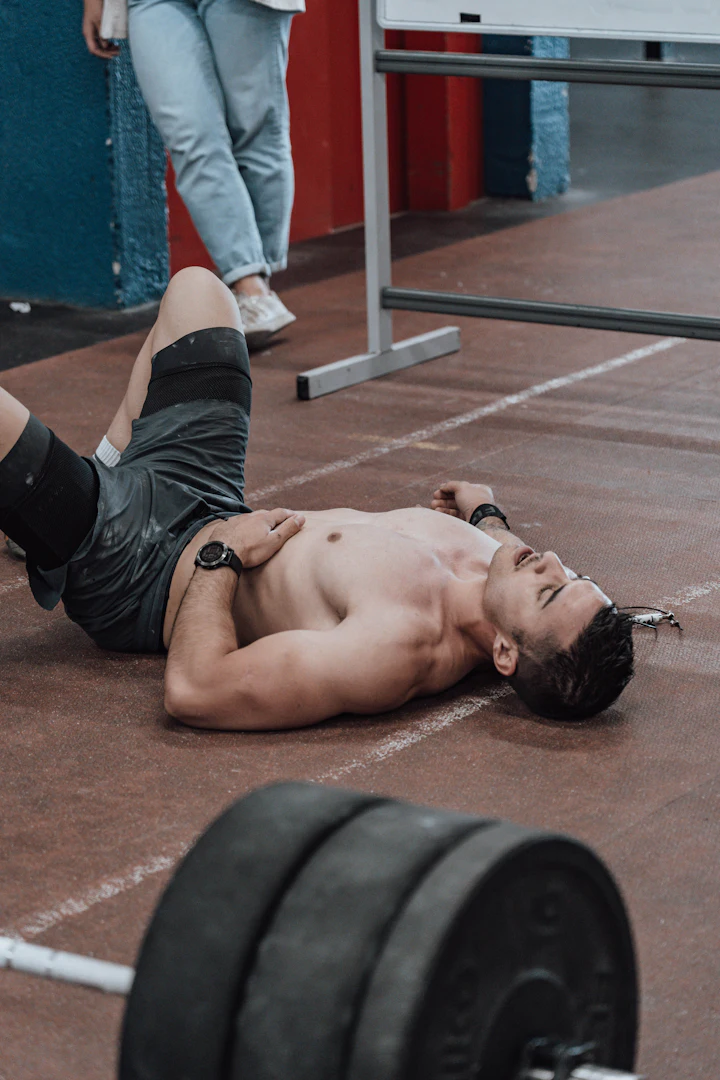Atleta de crossfit exausto no chão da box após o treino