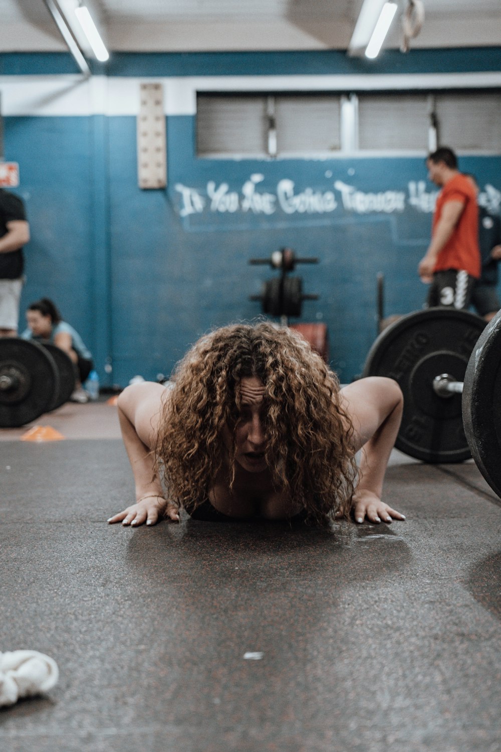 a woman squatting on the ground in a gym