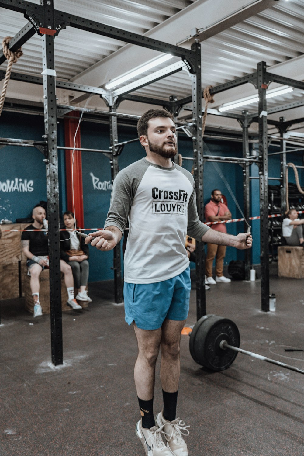 a man standing on a barbell in a crossfit gym