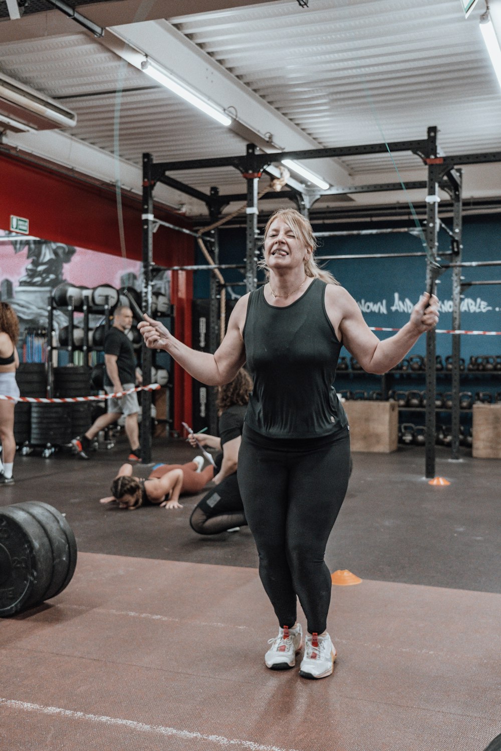a woman standing in a gym holding a barbell