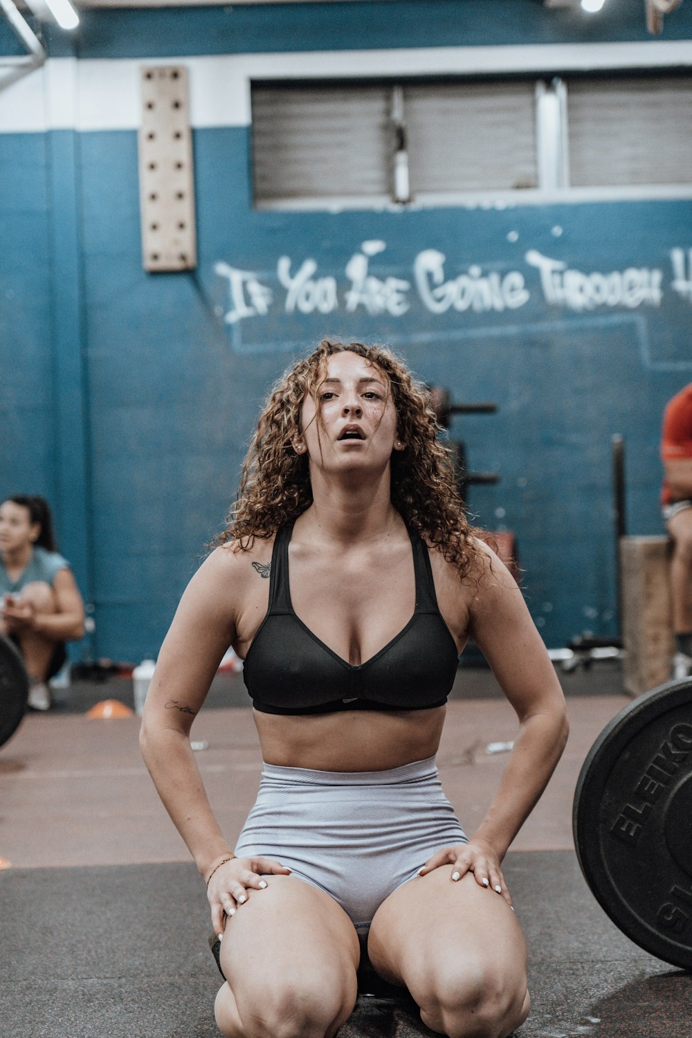 a woman squatting on the ground in a gym