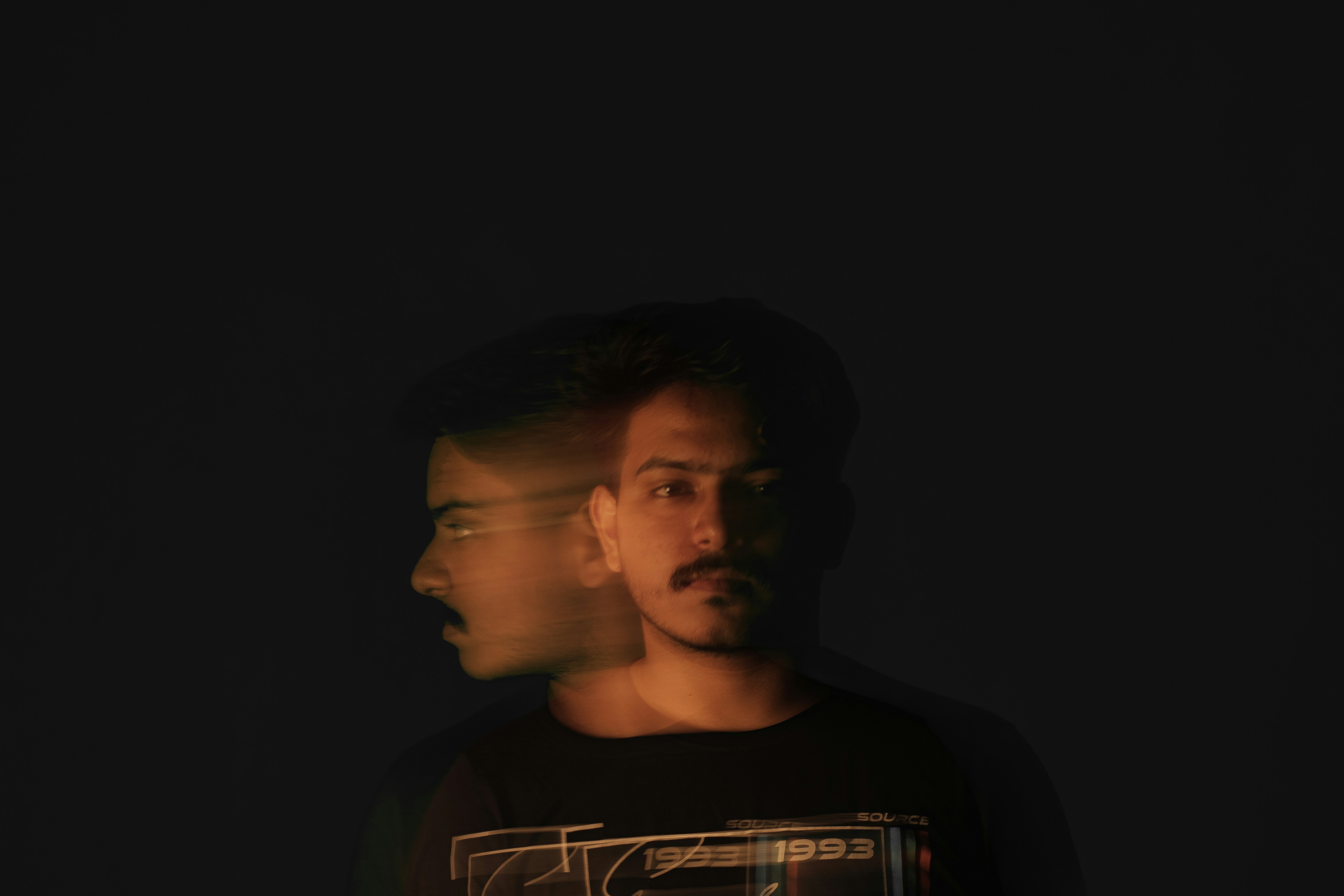 a man standing in the dark with his head turned to the side