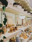 A cozy display of handcrafted cultural souvenirs arranged on a wooden shelf with green plants around.