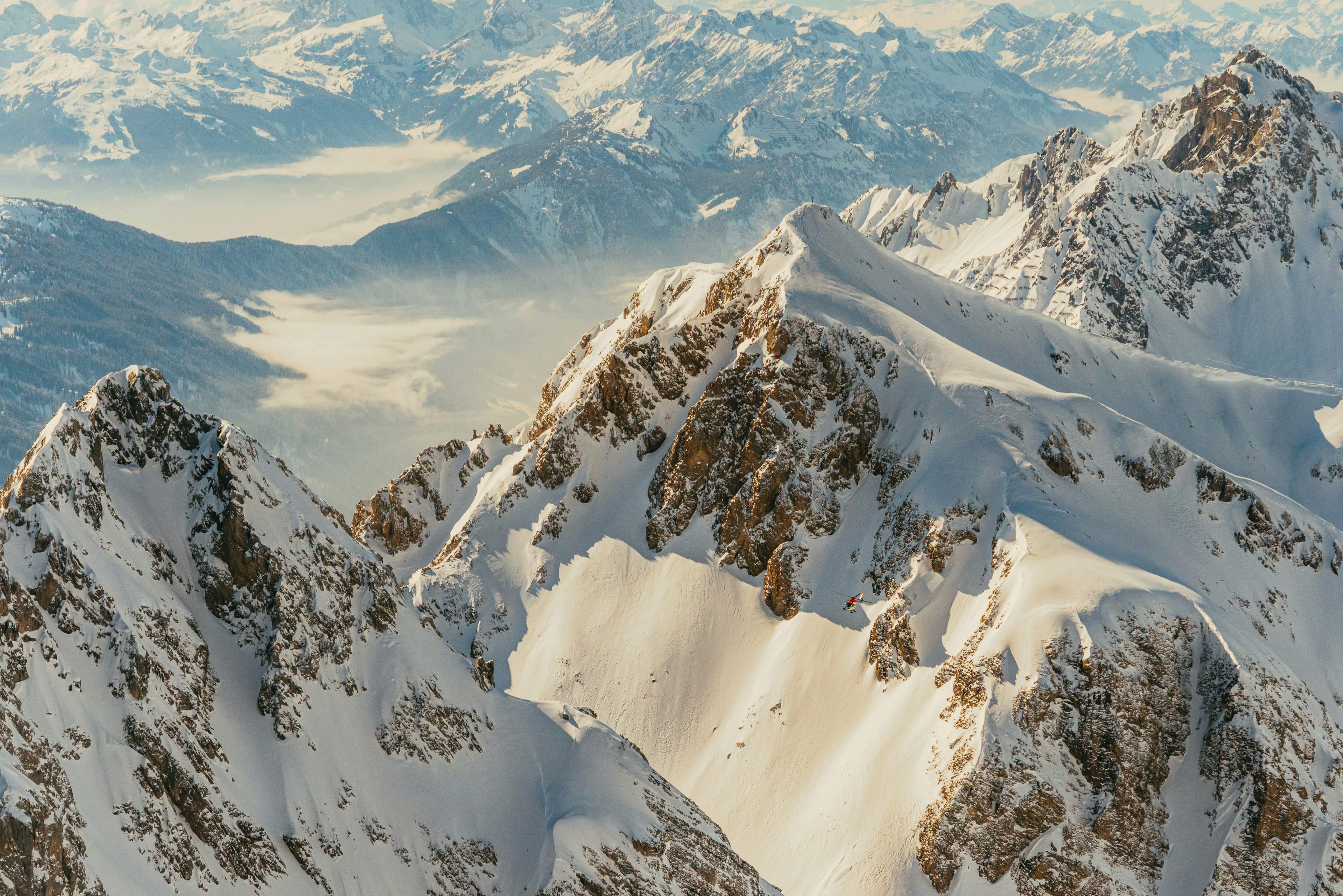 a mountain range covered in snow with mountains in the background, 