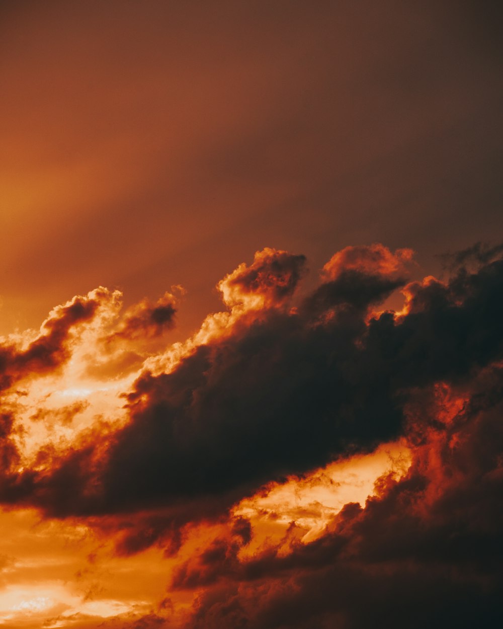 a plane flying through a cloudy sky at sunset