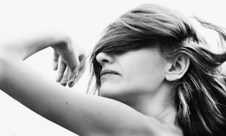 a black and white photo of a woman with her hair blowing in the wind
