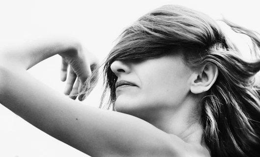 a black and white photo of a woman with her hair blowing in the wind