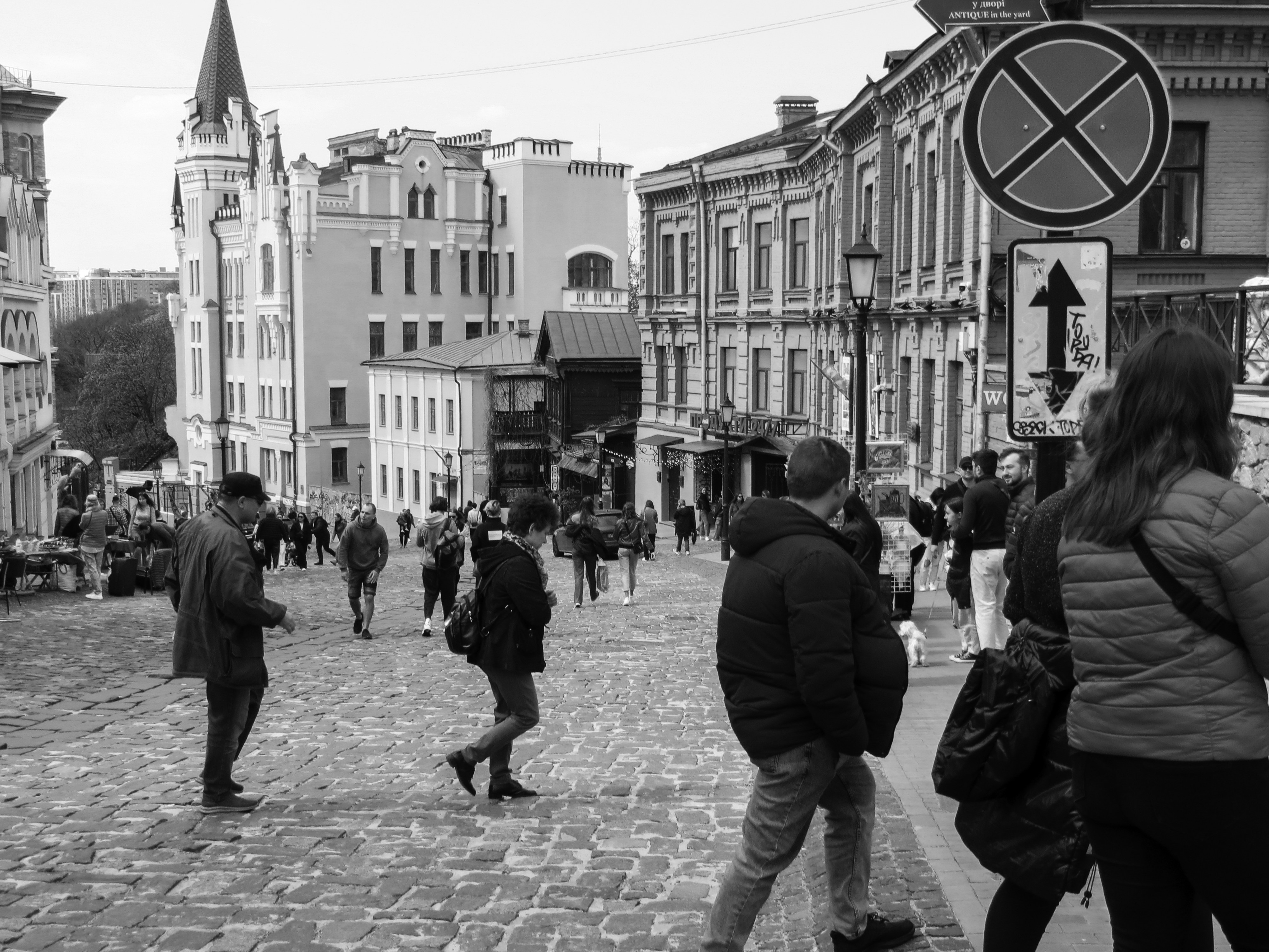 a group of people walking down a street next to tall buildings