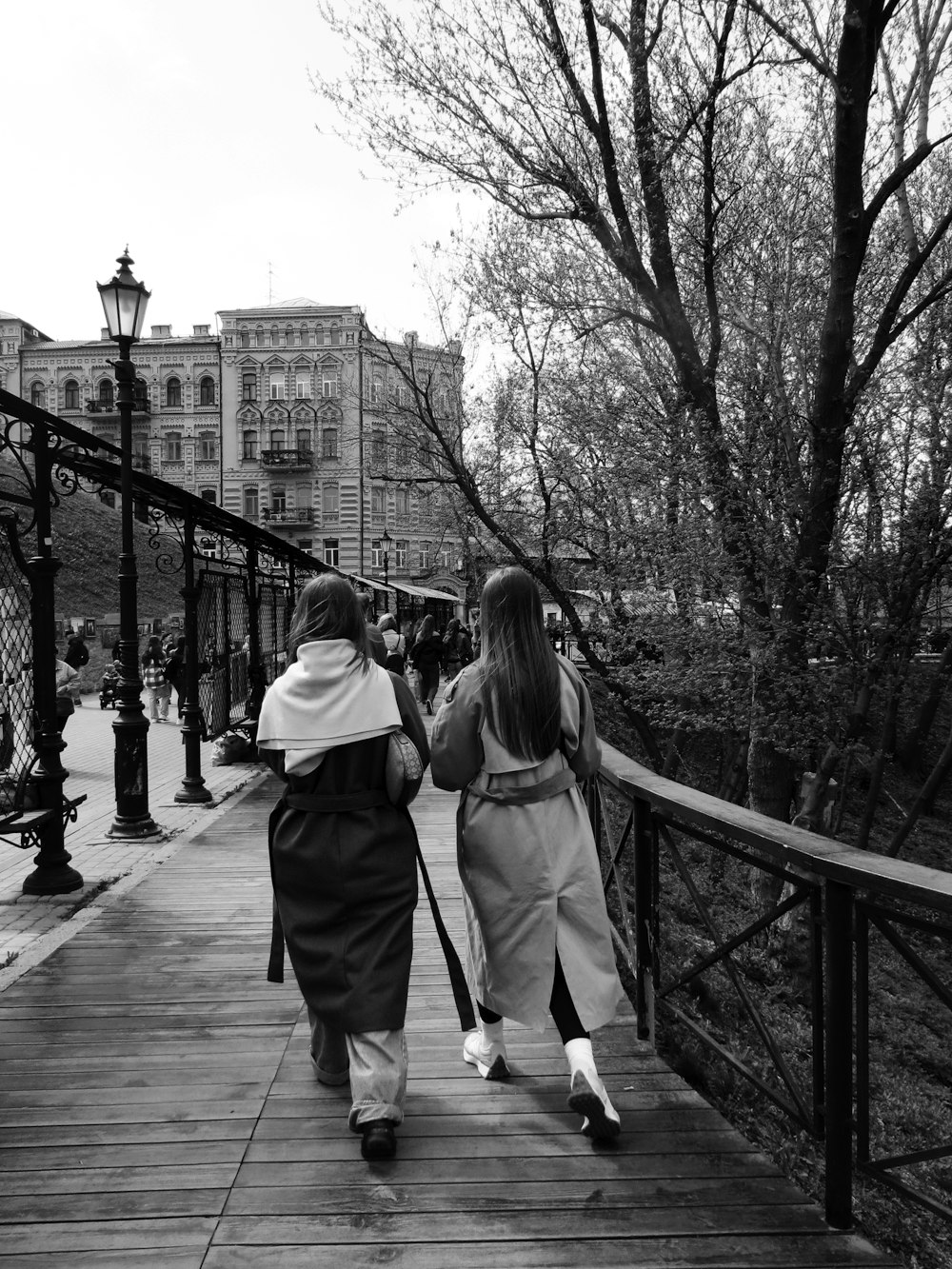 two women are walking down a wooden walkway