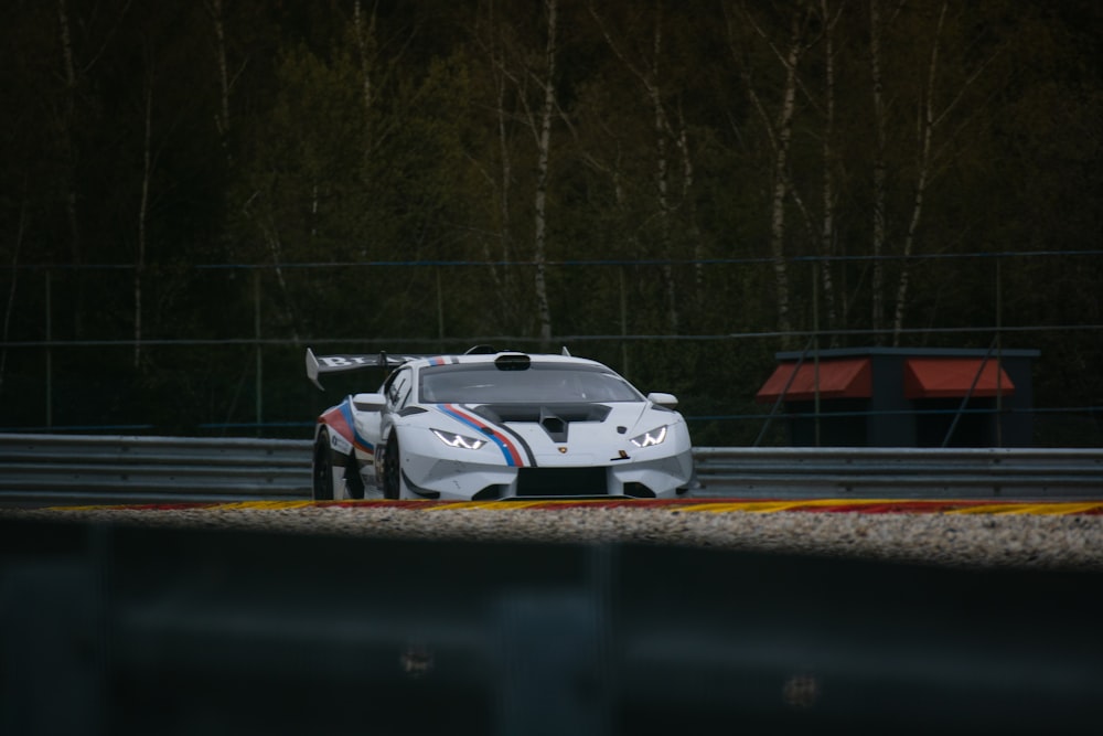 a car driving on a race track with trees in the background