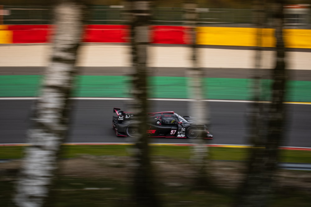 a car driving down a race track with trees in the foreground