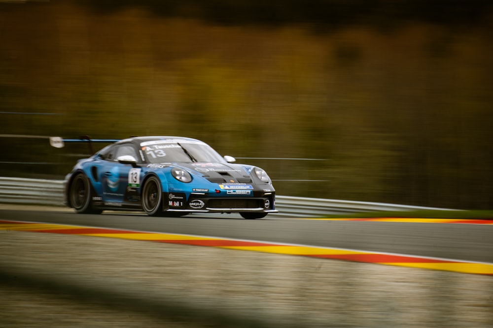 a blue sports car driving down a race track