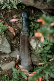 A sturdy machete resting on a wooden table surrounded by tropical fruits.