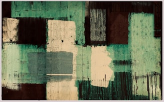 A textured abstract painting featuring rectangular and square shapes in various shades of green, brown, and cream. The surface is adorned with visible brush strokes and woodgrain textures, creating a rustic and layered appearance.