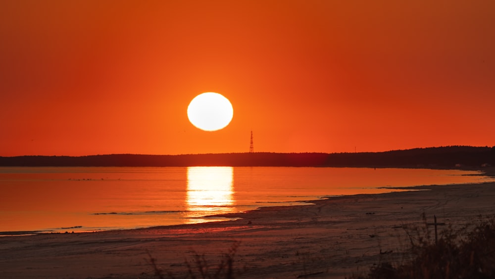 the sun is setting over the water at the beach