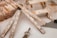 Assorted construction and woodworking tools arranged on a surface, including a folding ruler, a paintbrush with visible paint splatters, a small wooden stool or framework, a triangular ruler, a pencil, and a key. The objects appear well-used, suggesting frequent usage in woodworking or DIY projects.