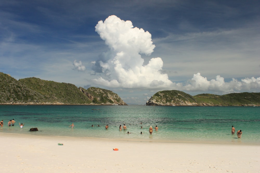 a group of people standing on top of a sandy beach