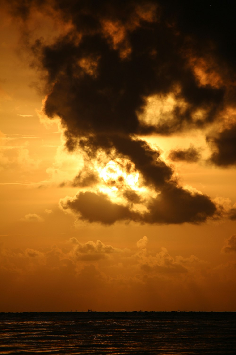 the sun is setting over the ocean with a boat in the distance