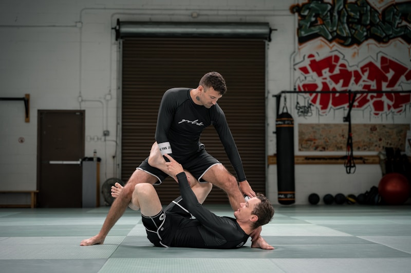 Two grapplers engaged in no-gi BJJ training on the mat