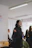 A focused young woman leading a small group prayer circle in a bright, modern church setting.