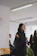 A focused young woman leading a small group prayer circle in a bright, modern church setting.