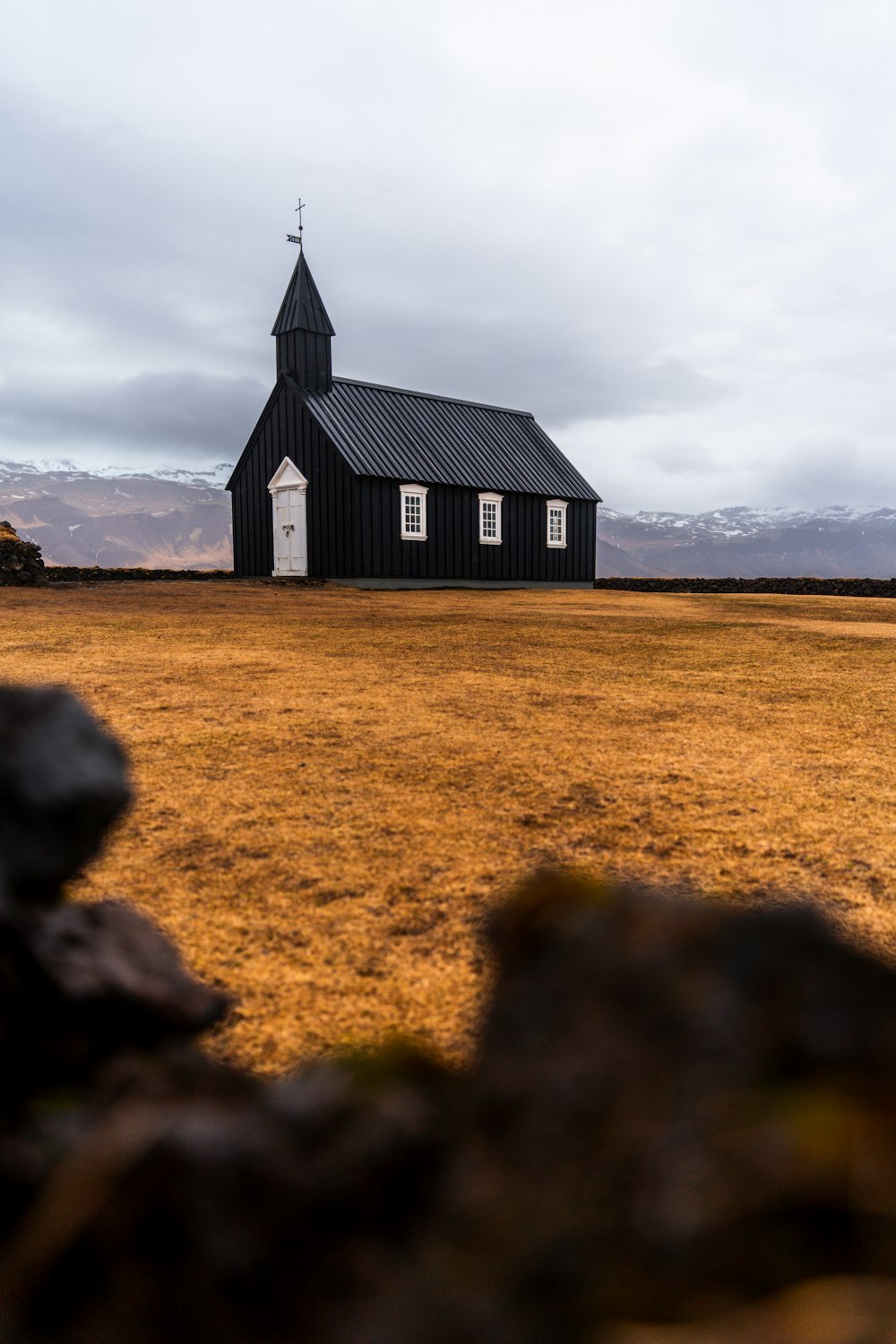 a black church with a steeple on a cloudy day