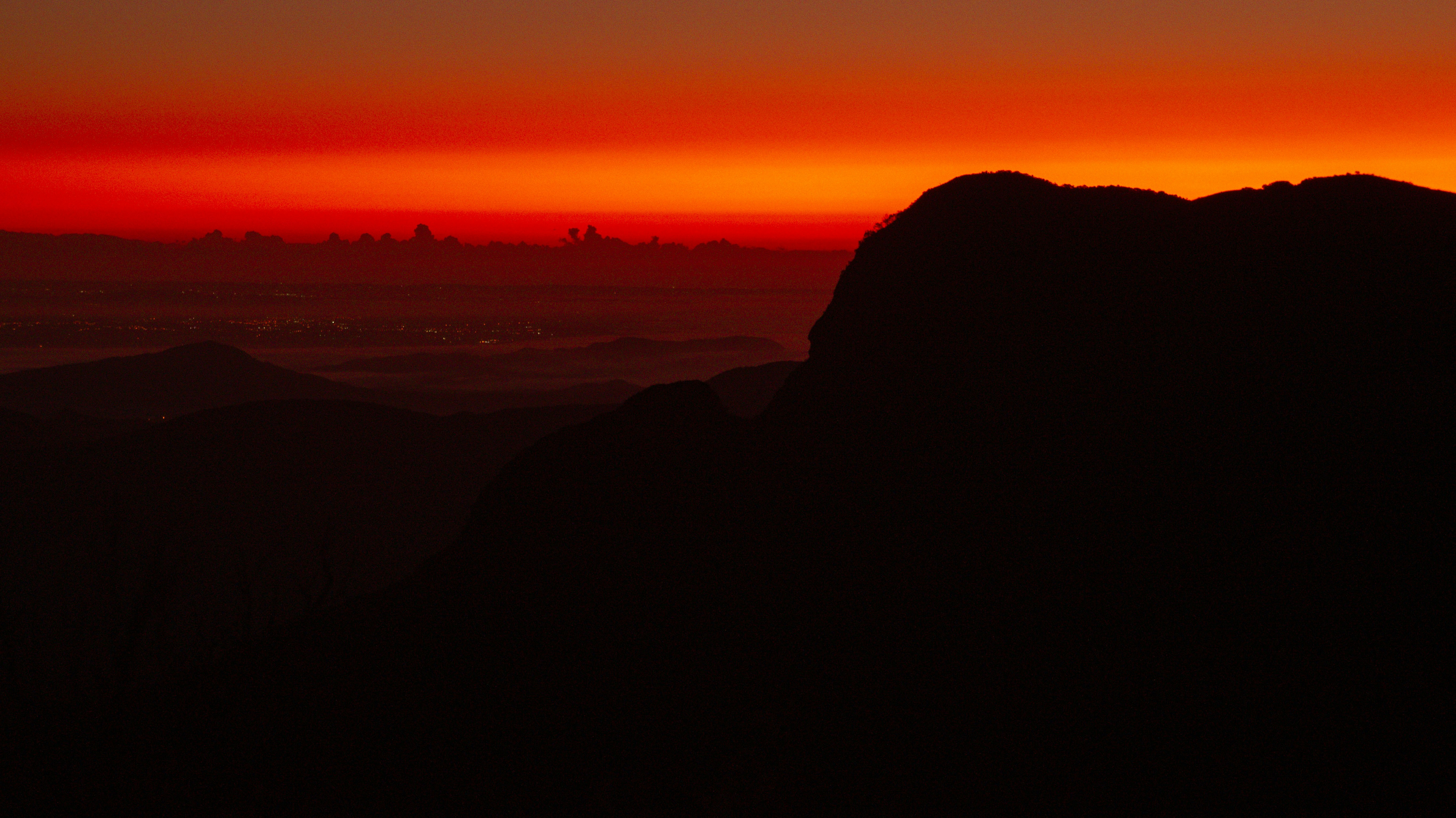 the sun is setting over a mountain range
