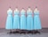 Five dress forms are aligned in a row, each displaying an identical light blue, sleeveless dress with a fitted bodice and a full skirt. They are placed on a gray patterned floor in front of a soft pink background.