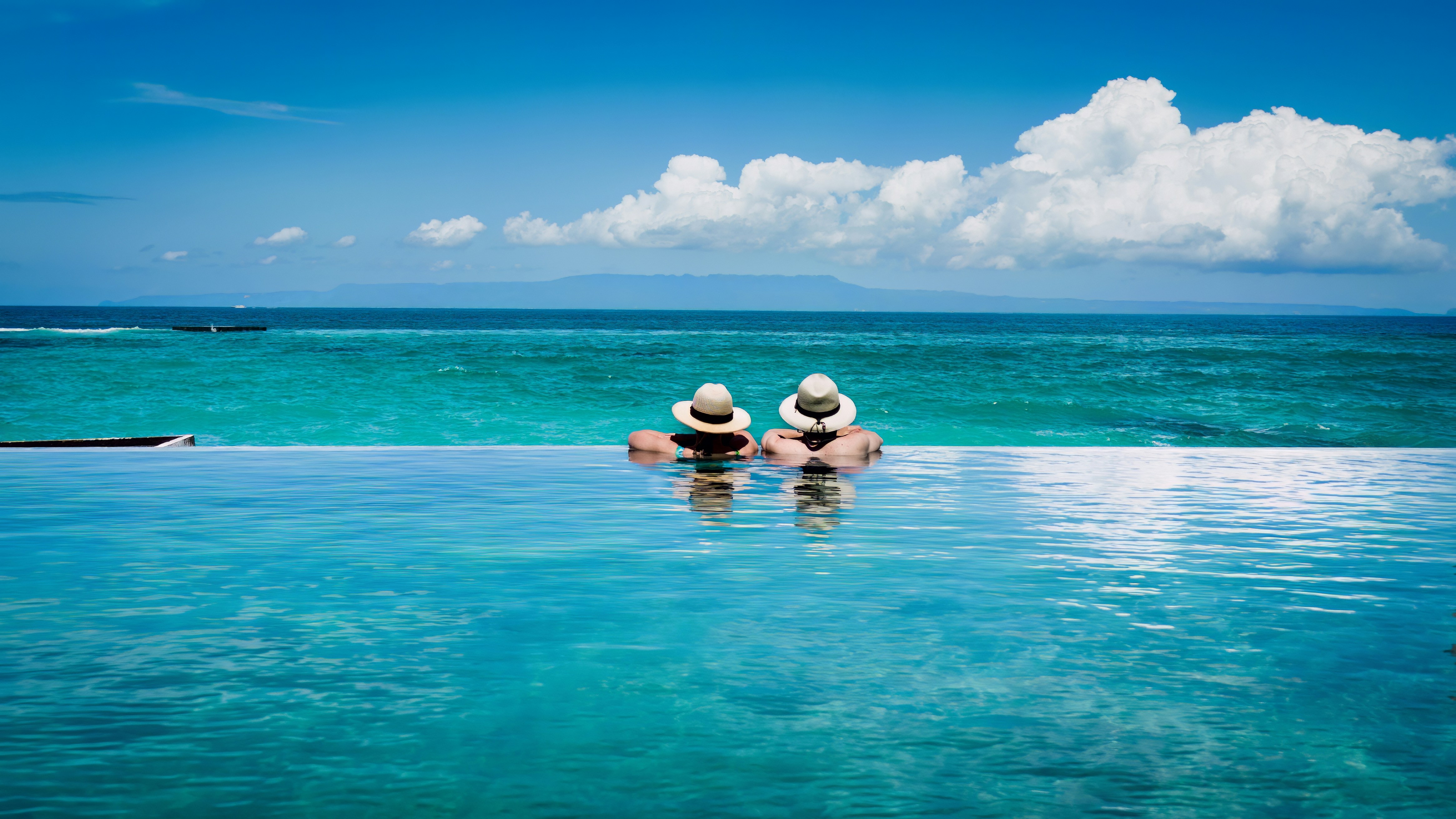 two people sitting on the edge of a swimming pool