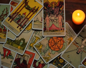 a candle sitting next to a pile of tarot cards