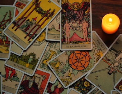 a candle sitting next to a pile of tarot cards