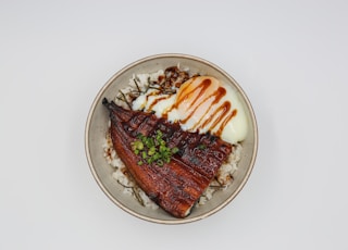 a white plate topped with meat and rice