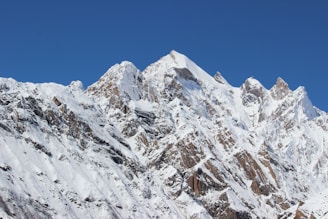 a large mountain covered in snow under a blue sky