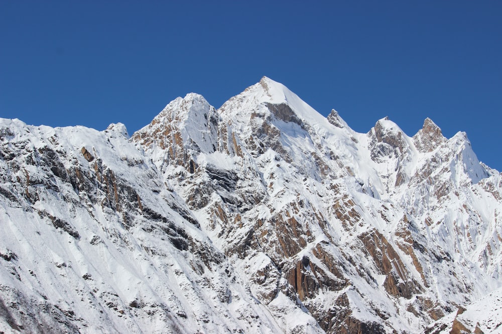 a large mountain covered in snow under a blue sky