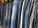 A row of jeans in various shades of blue and black is displayed on hangers in a clothing store. The jeans are arranged closely together, demonstrating a variety of washes and styles, from light blue to dark denim.
