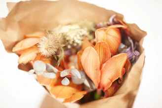 A charming bouquet of mixed seasonal blooms wrapped in brown paper.