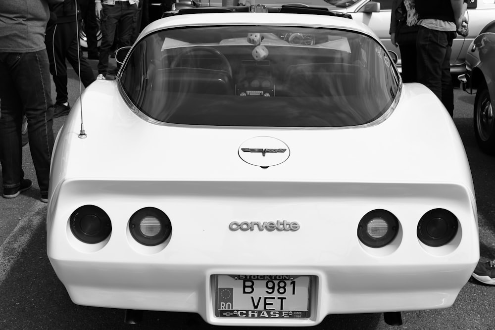 a white car parked in a parking lot next to a group of people