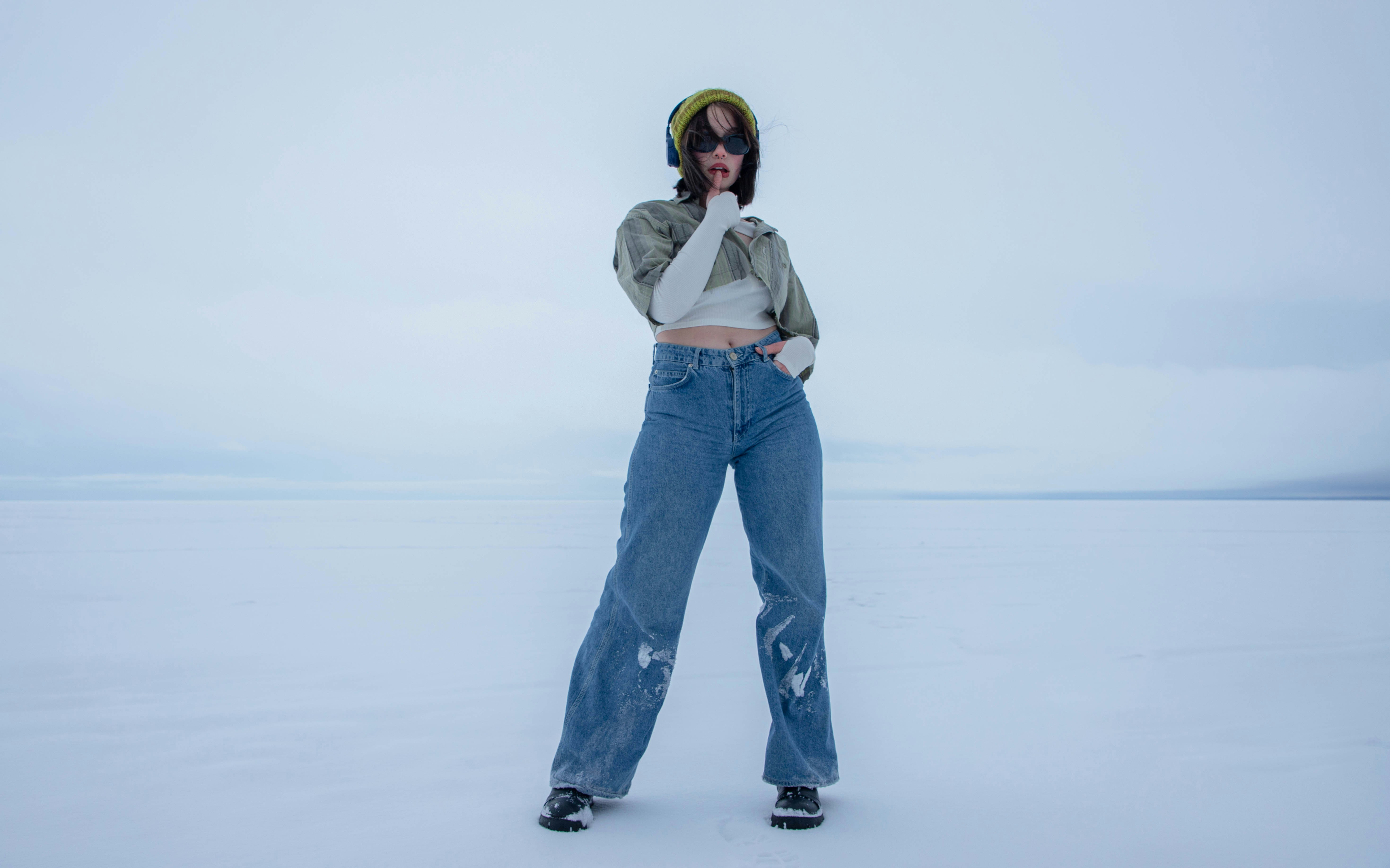 a woman standing in the middle of a snow covered field