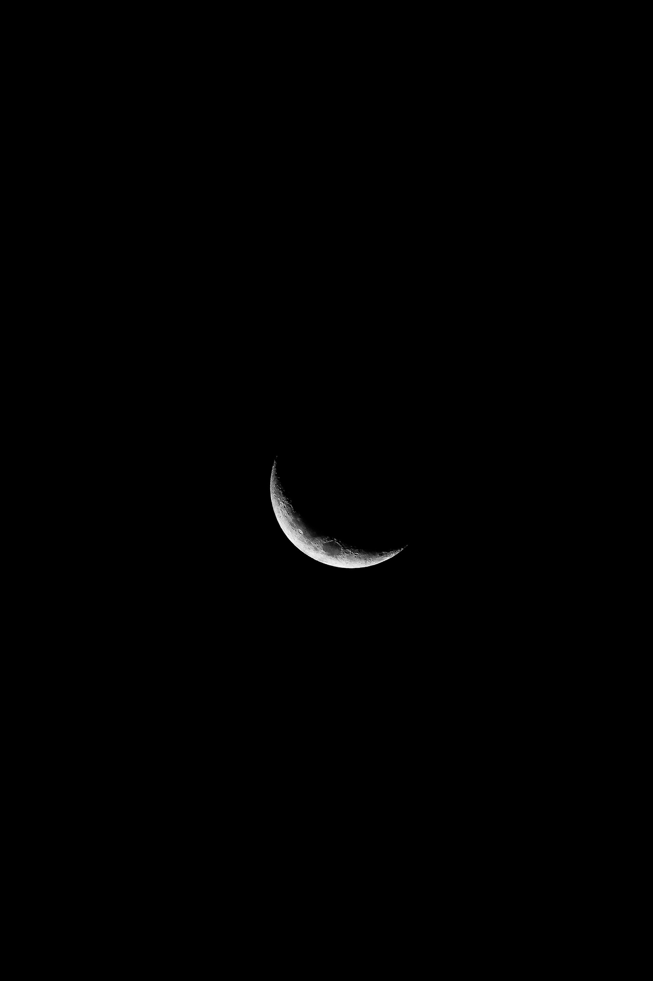 a crescent moon is seen in the dark sky