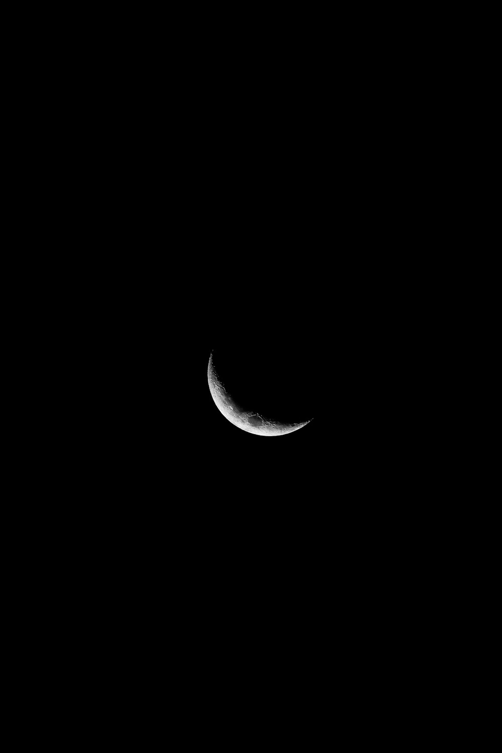 a crescent moon is seen in the dark sky