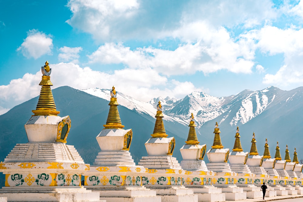 a row of white and gold buildings with mountains in the background