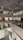 A modern art gallery with multiple levels and open spaces, featuring various artworks on the walls. The structure is illuminated by soft indoor lighting, highlighting paintings and photographs. The gallery features glass railings and a spacious, geometric design.