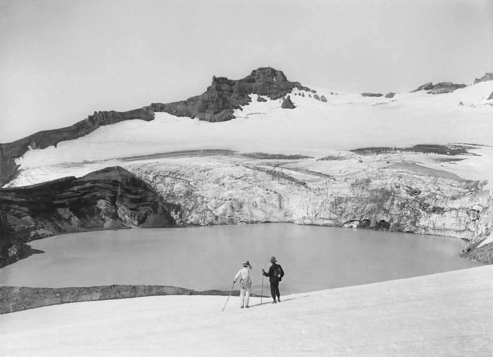 a couple of people standing on top of a snow covered slope