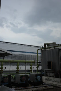A sturdy industrial shed cover protecting heavy machinery under a cloudy sky.