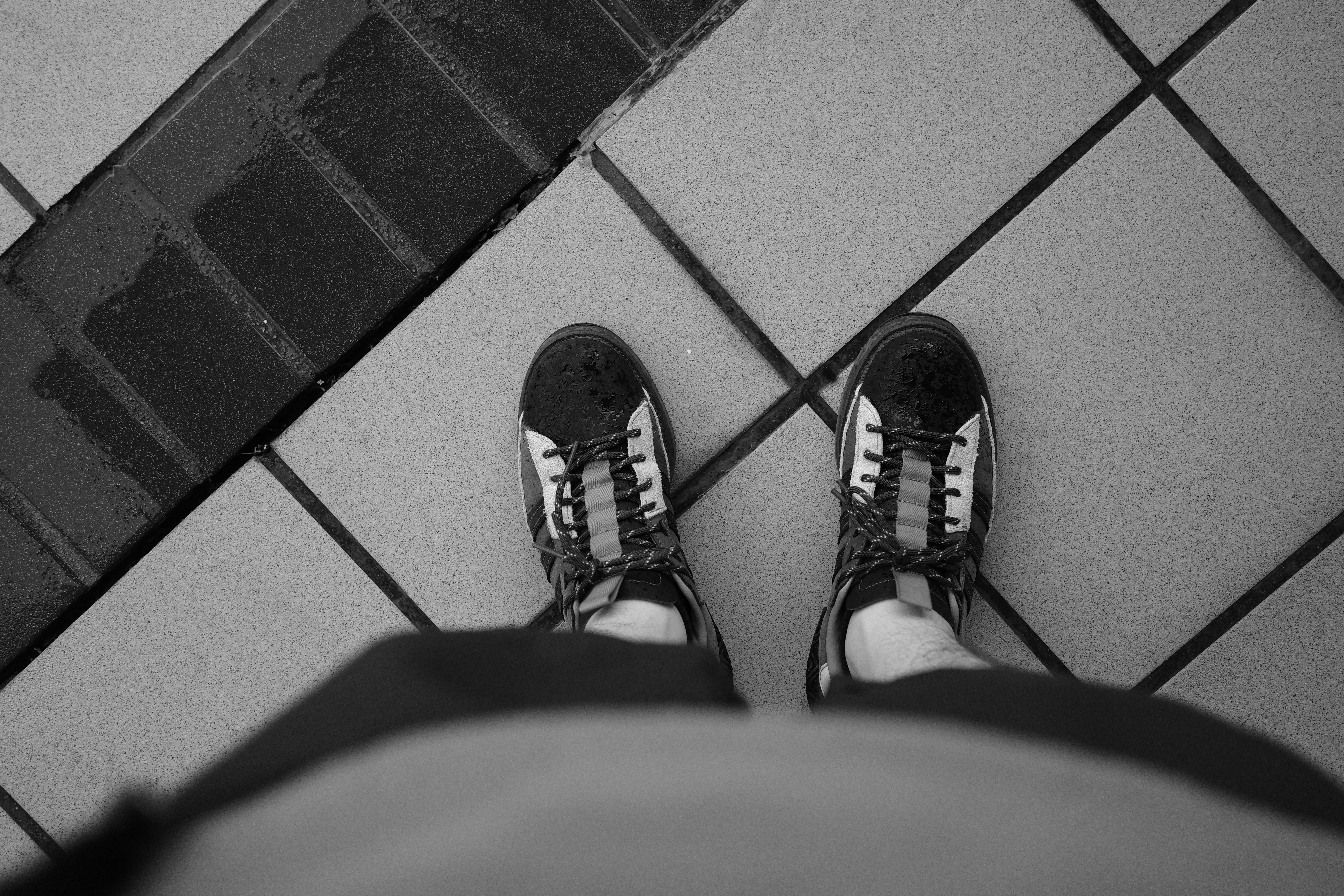 a person standing on a tile floor wearing black and white shoes